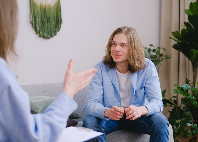 Young man with long hair in a therapy session, actively engaged in conversation.