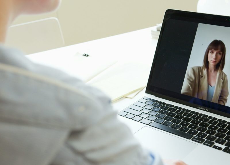 Close-up of woman on a video call using a laptop in a modern workspace.